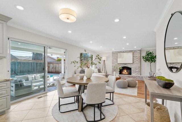 dining space with ornamental molding, plenty of natural light, light tile patterned flooring, and a fireplace