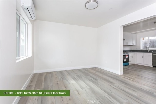 spare room with sink, a wall mounted AC, and light hardwood / wood-style floors