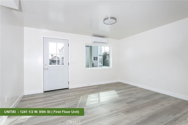 entrance foyer featuring a wealth of natural light, a wall unit AC, and light hardwood / wood-style floors