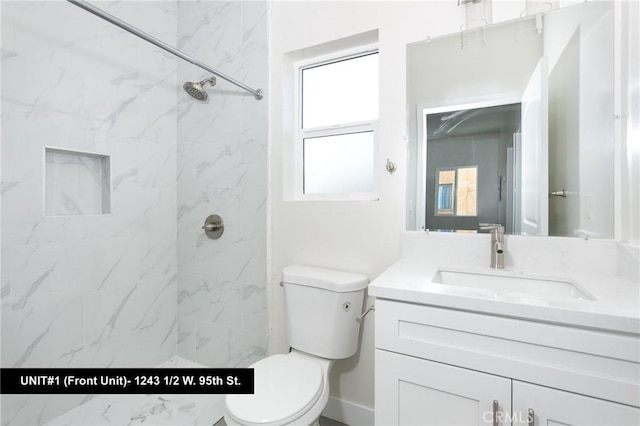 bathroom with vanity, toilet, and tiled shower