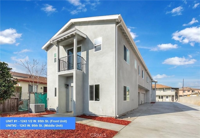 rear view of house with a balcony, a garage, and central AC unit