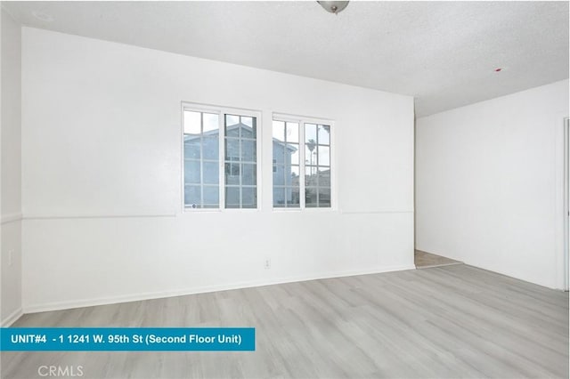 spare room featuring a textured ceiling and light hardwood / wood-style flooring