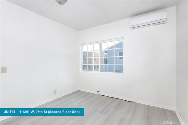 spare room with light hardwood / wood-style floors and a wall unit AC