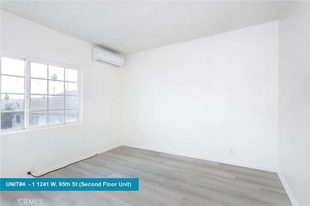 unfurnished room featuring a wall mounted AC and light hardwood / wood-style flooring