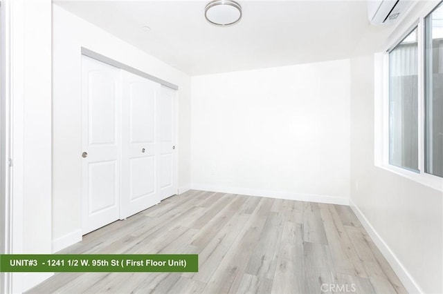 unfurnished bedroom with a wall mounted AC, light hardwood / wood-style floors, and a closet