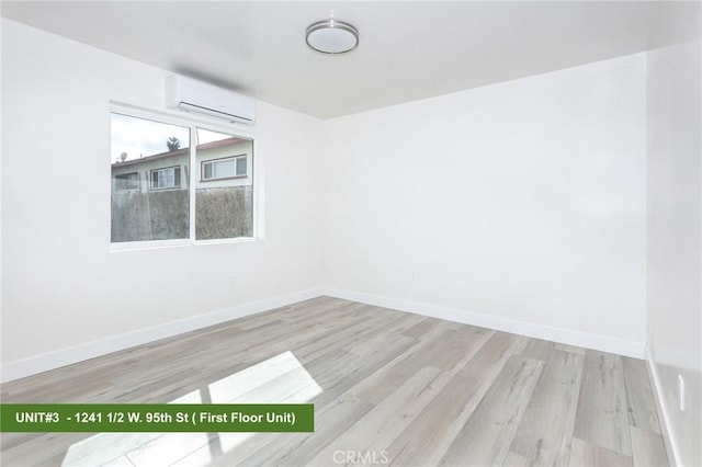 spare room with light wood-type flooring and an AC wall unit