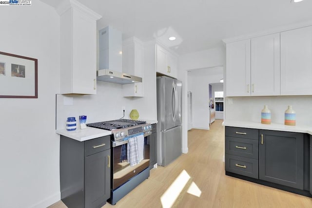 kitchen featuring gray cabinetry, white cabinets, light hardwood / wood-style floors, stainless steel appliances, and wall chimney exhaust hood