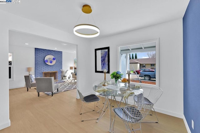 dining area featuring light hardwood / wood-style floors and a brick fireplace