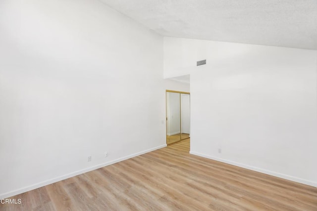 empty room featuring high vaulted ceiling and light hardwood / wood-style flooring