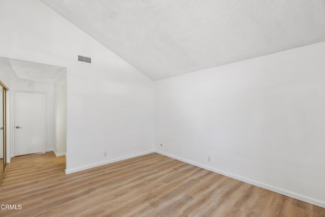 empty room with lofted ceiling and light hardwood / wood-style floors