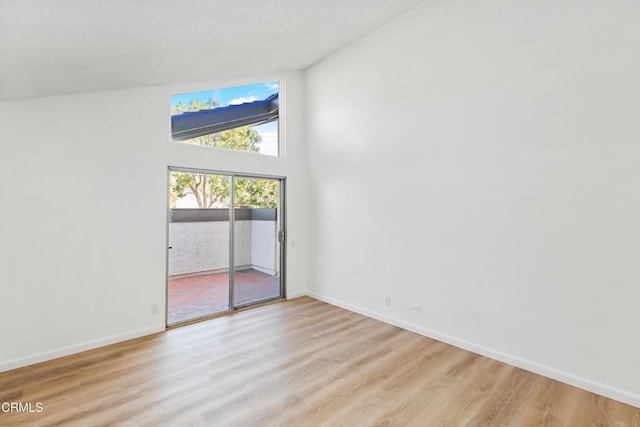 spare room with high vaulted ceiling and light wood-type flooring