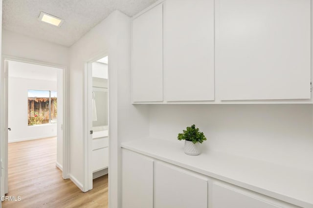 corridor featuring light hardwood / wood-style flooring and a textured ceiling