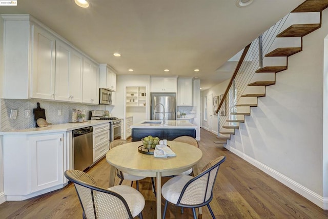 kitchen with backsplash, stainless steel appliances, an island with sink, and white cabinets