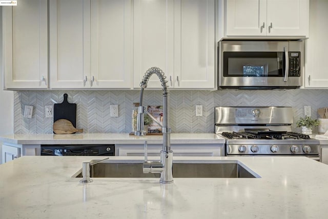 kitchen featuring light stone counters, stainless steel appliances, backsplash, and white cabinets