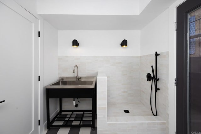 bathroom with sink, a tile shower, and tile walls