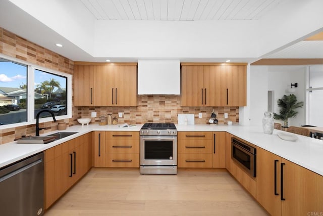 kitchen featuring wall chimney exhaust hood, light brown cabinetry, sink, tasteful backsplash, and appliances with stainless steel finishes