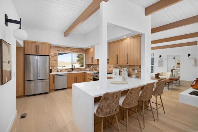 kitchen with sink, a breakfast bar area, stainless steel appliances, tasteful backsplash, and kitchen peninsula