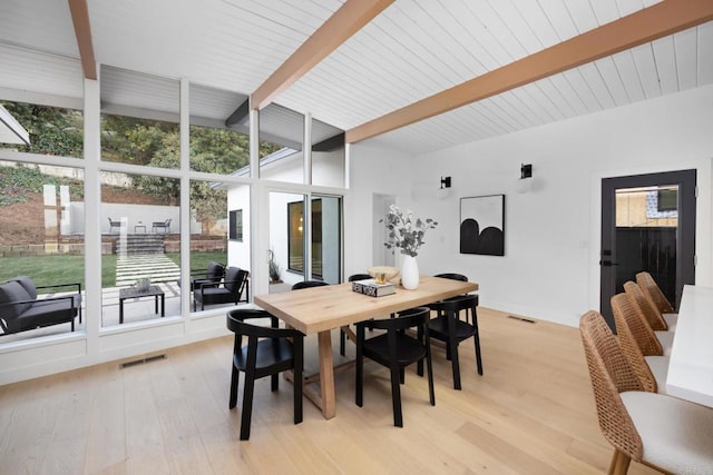 dining space with beamed ceiling, expansive windows, and light hardwood / wood-style floors