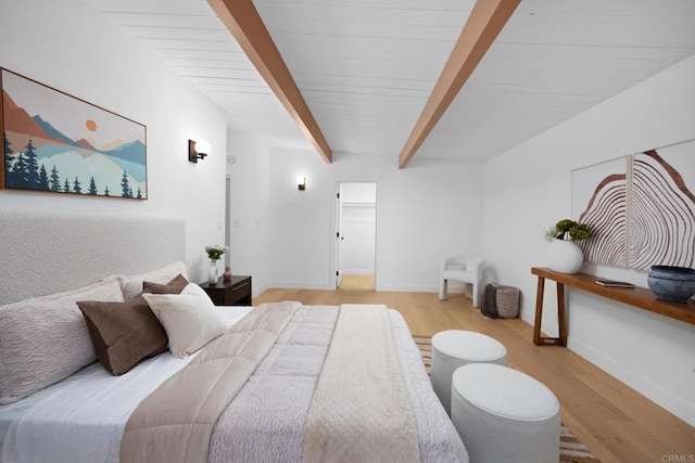 bedroom featuring light hardwood / wood-style flooring and beamed ceiling