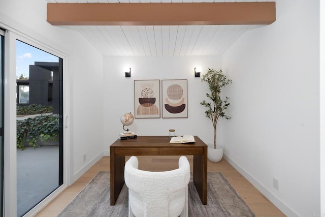 home office featuring light wood-type flooring and beam ceiling