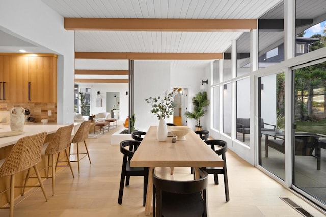 dining space featuring beamed ceiling, floor to ceiling windows, and light wood-type flooring