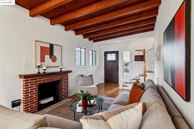 living room with beamed ceiling, a brick fireplace, and hardwood / wood-style flooring