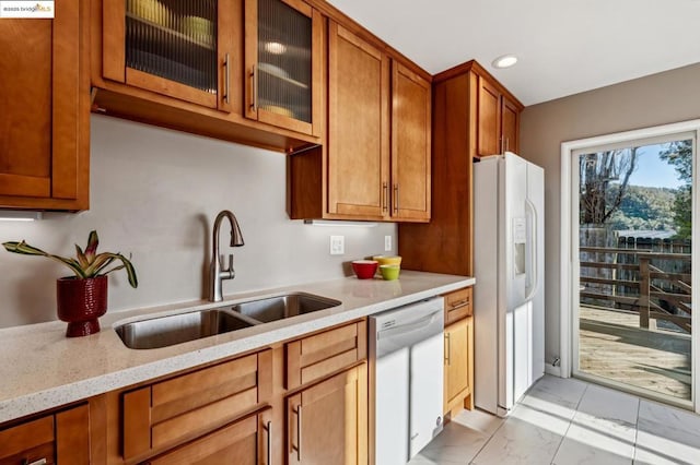 kitchen featuring dishwasher, light stone countertops, white fridge with ice dispenser, and sink