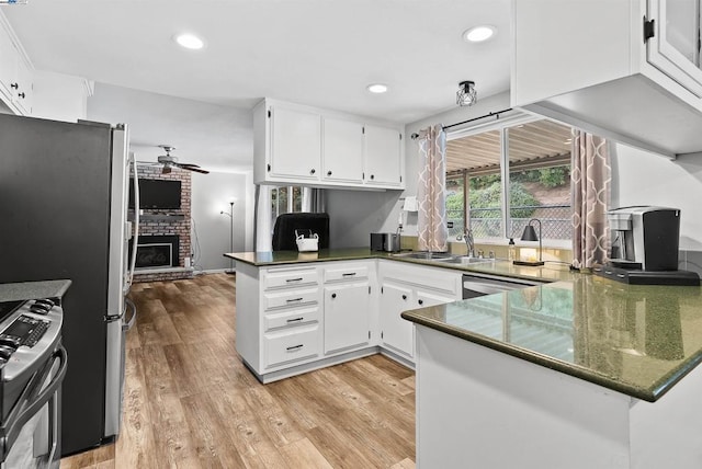 kitchen with stainless steel appliances, white cabinetry, a fireplace, and kitchen peninsula