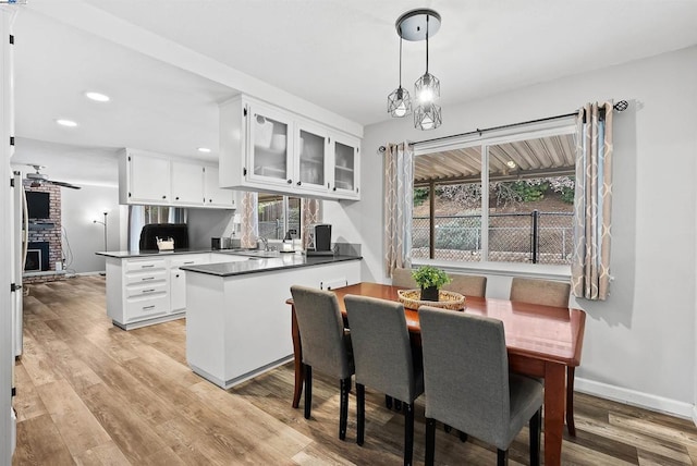 kitchen featuring white cabinetry, pendant lighting, light wood-type flooring, and kitchen peninsula