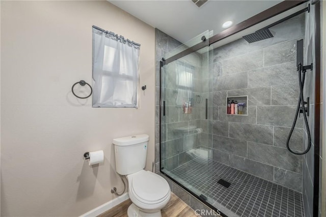 bathroom featuring a shower with door, hardwood / wood-style floors, and toilet