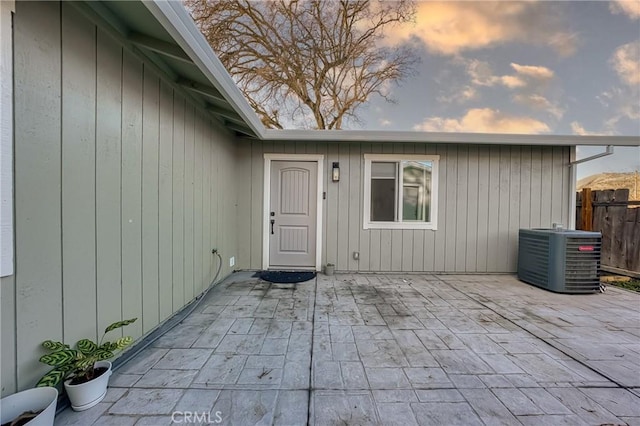 exterior entry at dusk featuring central AC unit and a patio area