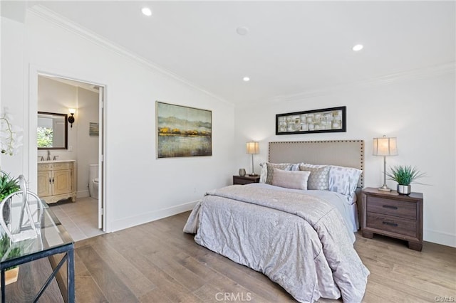 bedroom with crown molding, lofted ceiling, sink, and light hardwood / wood-style flooring