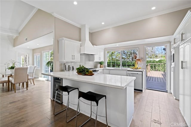 kitchen featuring hardwood / wood-style flooring, dishwasher, white cabinets, custom exhaust hood, and kitchen peninsula