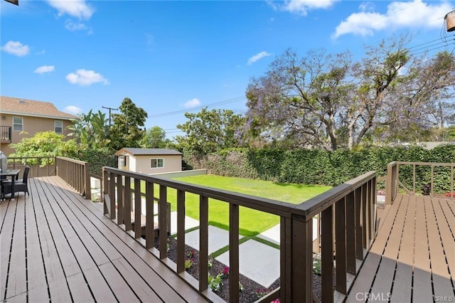 wooden terrace featuring an outdoor structure and a yard