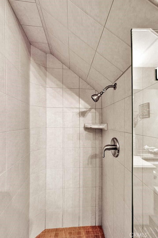 bathroom with tiled shower and lofted ceiling