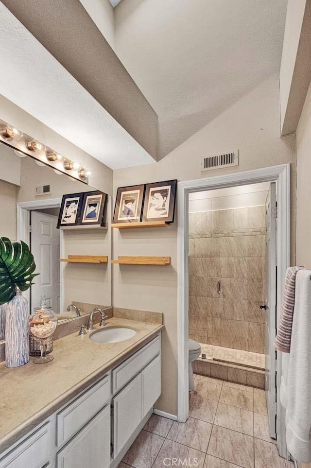 bathroom with tiled shower, vanity, toilet, and vaulted ceiling