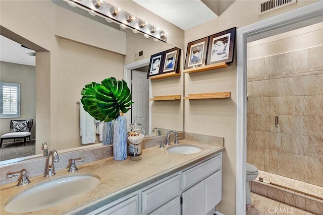 bathroom with vanity, a tile shower, and toilet