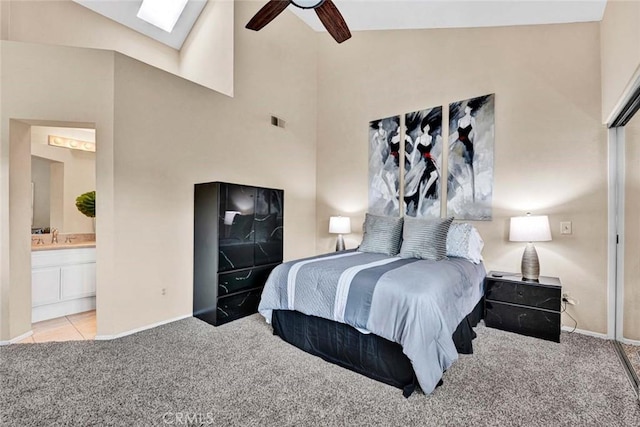 carpeted bedroom with sink, ensuite bath, lofted ceiling with skylight, and ceiling fan