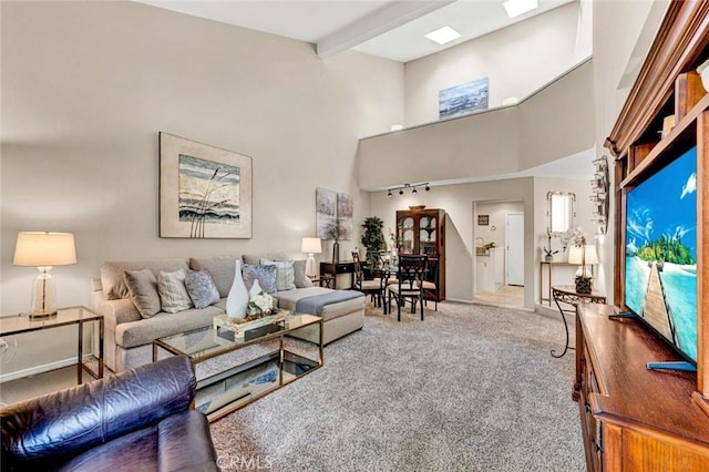 living room featuring beam ceiling, carpet, and a high ceiling