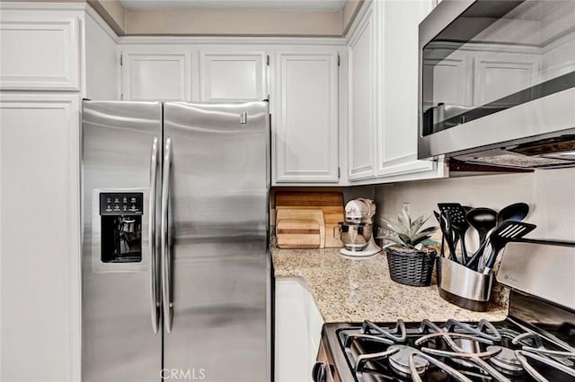 kitchen with white cabinetry, stainless steel appliances, and light stone counters