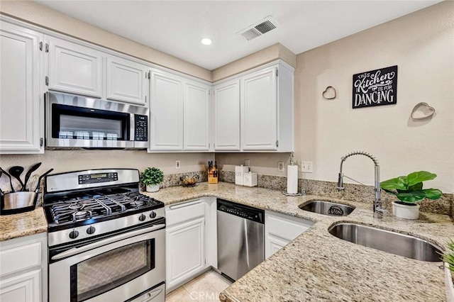 kitchen with white cabinetry, appliances with stainless steel finishes, and light stone counters