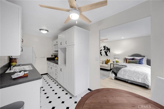 kitchen featuring ceiling fan, black electric stovetop, sink, and white cabinets