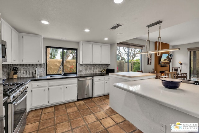 kitchen with white cabinetry, sink, decorative light fixtures, and stainless steel appliances