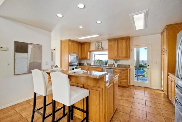 kitchen featuring a sink, a breakfast bar area, light tile patterned floors, and stainless steel appliances