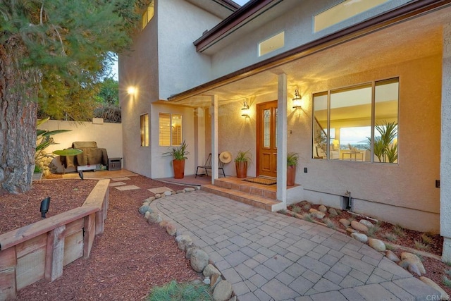 doorway to property with stucco siding and fence