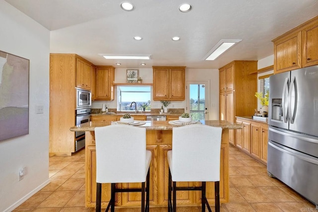 kitchen with a breakfast bar, light tile patterned floors, a kitchen island, and stainless steel appliances