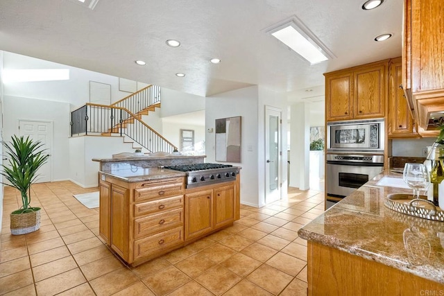 kitchen with light tile patterned floors, stainless steel appliances, a kitchen island, and recessed lighting