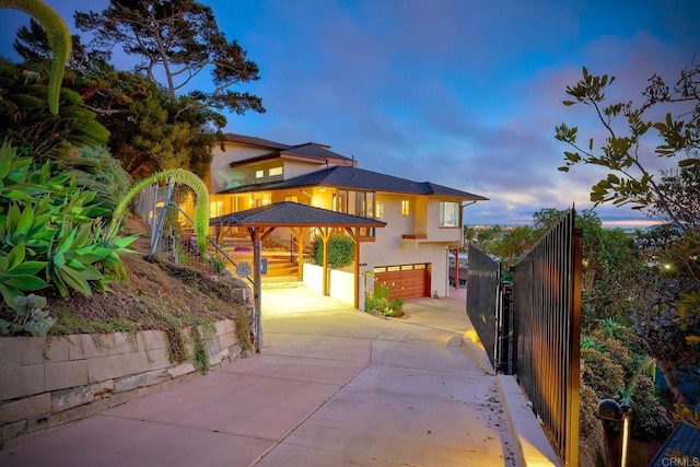 exterior space featuring stucco siding, concrete driveway, an attached garage, and fence