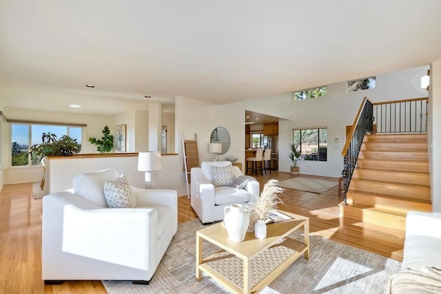 living area featuring baseboards, light wood-style floors, and stairs