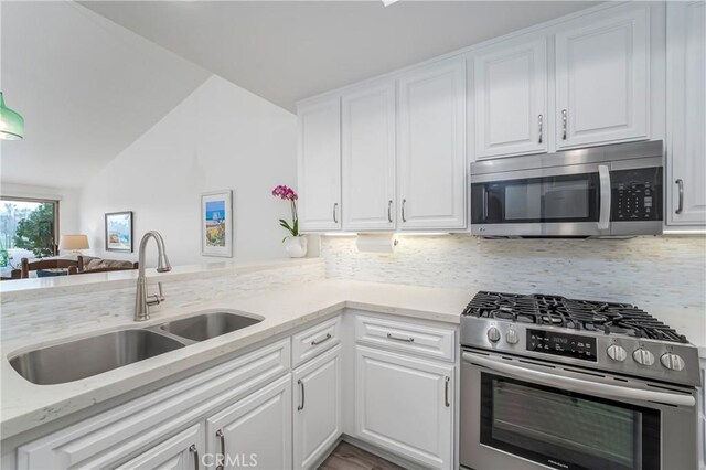 kitchen featuring sink, light stone counters, appliances with stainless steel finishes, white cabinets, and backsplash